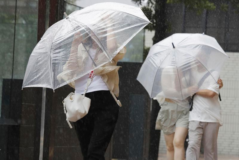 People holding umbrella, struggle with the strong wind as a typhoon is approaching in Fukuoka, western Japan, Thursday, Aug. 29, 2024. (Kyodo News via AP)