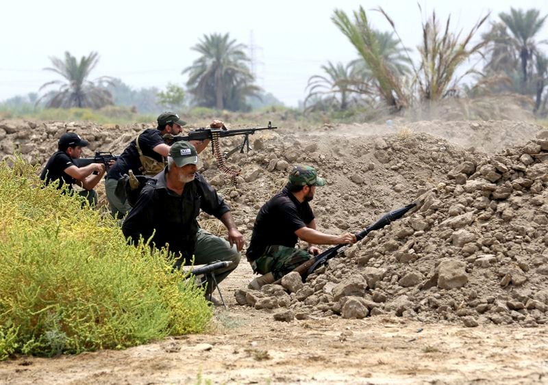 FILE - Iraq Shiite fighters prepare to fight militants from the extremist Islamic State group in Jurf al-Sakhar, 43 miles (70 kilometers) south of Baghdad, Iraq, Aug 18, 2014. Ten years after the Islamic State group declared its caliphate in large parts of Iraq and Syria, the extremists now control no land, have lost many prominent founding leaders and are mostly away from the world news headlines. (AP Photo/Hadi Mizban, File)