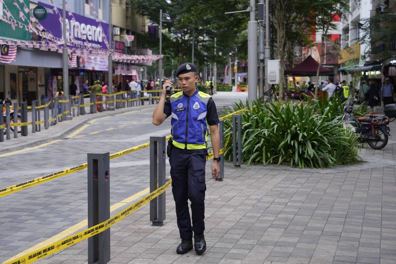 Police stand guard on a closed roadside after another deep sinkhole appeared a week after a woman fell into a sinkhole when a sidewalk caved in in Kuala Lumpur, Thursday, Aug. 29, 2024. (AP Photo/Vincent Thian)