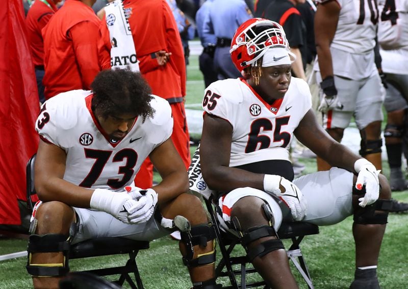 Georgia offensive lineman Xavier Truss (left) and Amarius Mims sit dejected and stunned on the sidelines in the final minutes of a 41-24 loss to Alabama in the SEC Championship game on Saturday, Dec 4, 2021, in Atlanta.   “Curtis Compton / Curtis.Compton@ajc.com”`