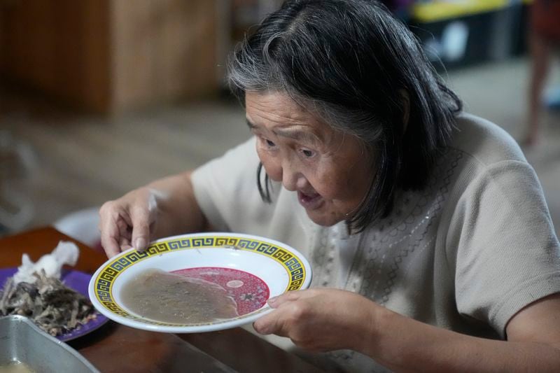 Marie Carl, 75, sits at the kitchen table at her home on Saturday, Aug. 17, 2024, in Mertarvik, Alaska. (AP Photo/Rick Bowmer)