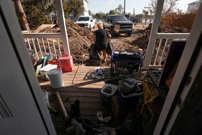 Pam Keen cleans up after their house took on water and piles of seaweed from the storm surge, in the aftermath of Hurricane Helene, in Steinhatchee, Fla., Saturday, Sept. 28, 2024. (AP Photo/Gerald Herbert)