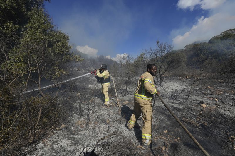 Israeli firefighters work to extinguish a fire after a rocket fired from Lebanon hit an open field in northern Israel, Wednesday, Sept. 18, 2024. (AP Photo/Baz Ratner)