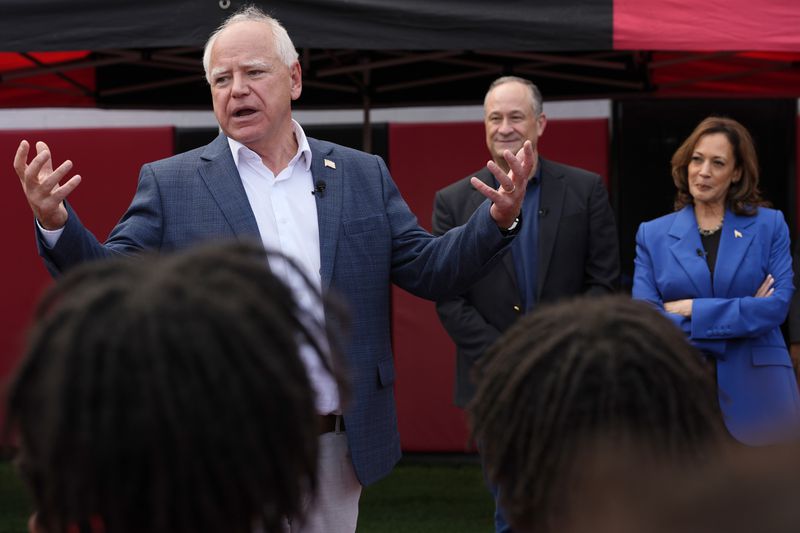 Democratic vice presidential nominee Minnesota Gov. Tim Walz speaks as Democratic presidential nominee Vice President Kamala Harris, right, and second gentleman Doug Emhoff listen during a campaign stop to greet members of the Aliquippa High School football team at their school, Sunday, Aug. 18, 2024, in Aliquippa, Pa. (AP Photo/Julia Nikhinson)