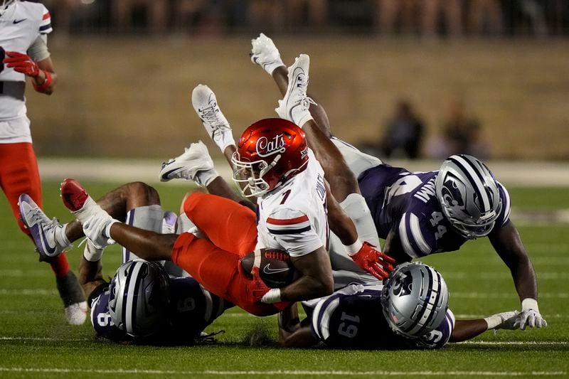 Arizona running back Jacory Croskey-Merritt (1) is tackled by Kansas State safety Jordan Riley (6), safety VJ Payne (19) and defensive end Tobi Osunsanmi (44) during the first half of an NCAA college football game Friday, Sept. 13, 2024, in Manhattan, Kan. (AP Photo/Charlie Riedel)