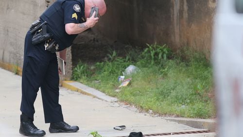 An Atlanta police officer checks on a gun found near the Martin Luther King Jr. Federal Building in downtown Atlanta. JOHN SPINK / JSPINK@AJC.COM