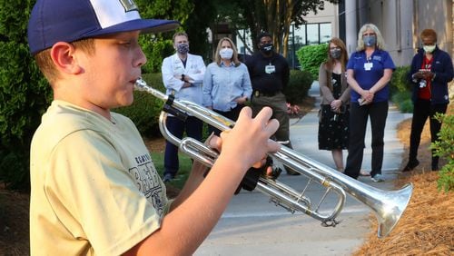 Medical staff pause to listen while local sixth grader Jason Zgonc plays show tunes and classical music on his trumpet outside Emory Decatur Hospital to entertain, thank and inspire the front-line heroes. The young trumpeter has become the talk of the facility, showing up at sunset for weeks. CURTIS COMPTON / CCOMPTON@AJC.COM