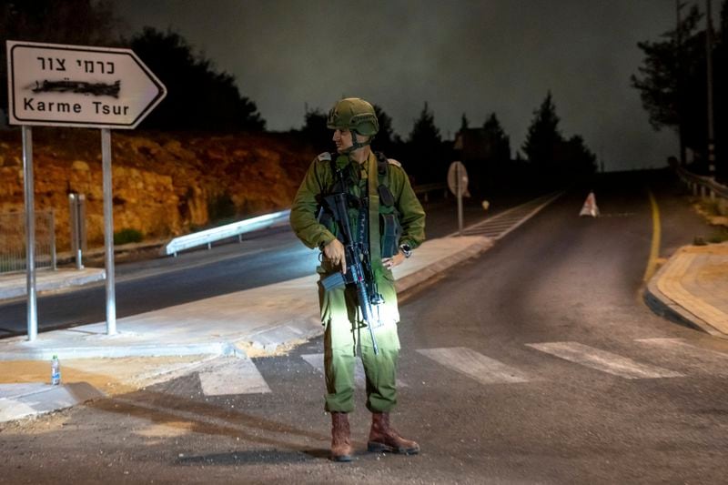 An Israeli soldier stands guard the near the scene of a car that exploded in the West Bank settlement of Karme Tsur, Saturday, Aug. 31, 2024. (AP Photo/Ohad Zwigenberg)