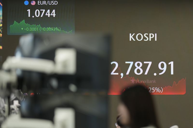 A currency trader watches computer monitors near the screens showing the Korea Composite Stock Price Index (KOSPI), right, and the foreign exchange rate at a foreign exchange dealing room in Seoul, South Korea, Wednesday, July 3, 2024. Asian shares were mostly higher on Wednesday after Tesla gained more than 10%, helping to drive U.S. benchmarks to more records. (AP Photo/Lee Jin-man)