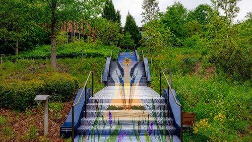 A new staircase mural at the Chattahoochee Nature Center depicts a pair of Great Blue Herons standing in the riverbed among native cattail and pickerelweed. In the background, a vibrant sunset highlights trees along the riverbank. Courtesy Chattahoochee Nature Center