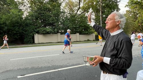 The Rev. Sam Candler of the Cathedral of St. Philip blessed runners with holy water. (Photo: Anjali Huynh/AJC)