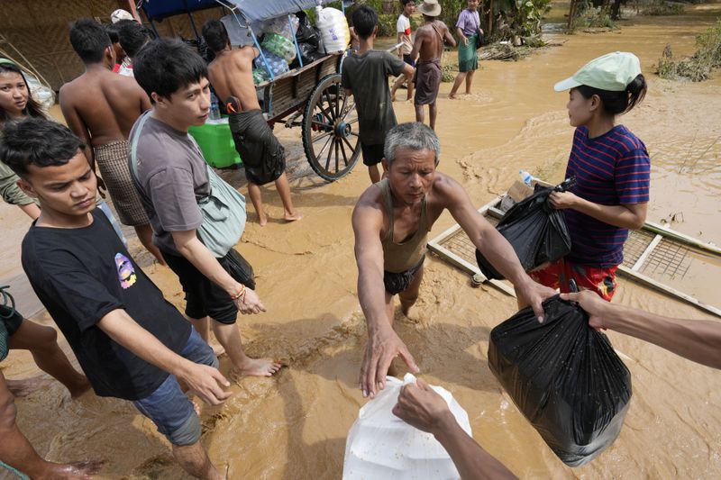 Local residents carrying food wade through a flooded road in Naypyitaw, Myanmar, Saturday, Sept. 14, 2024. (AP Photo/Aung Shine Oo)