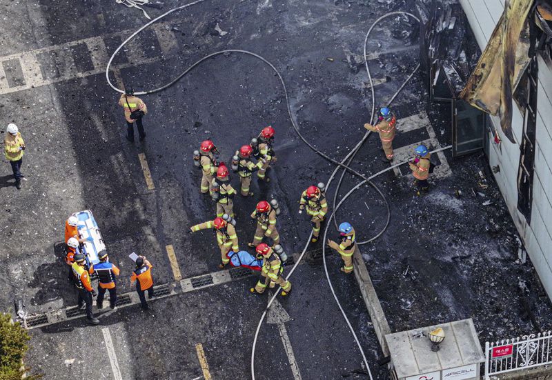 Firefighters carry a body at the site of a fire at a lithium battery manufacturing factory in Hwaseong, South Korea, Monday, June 24, 2024. (Newsis via AP)