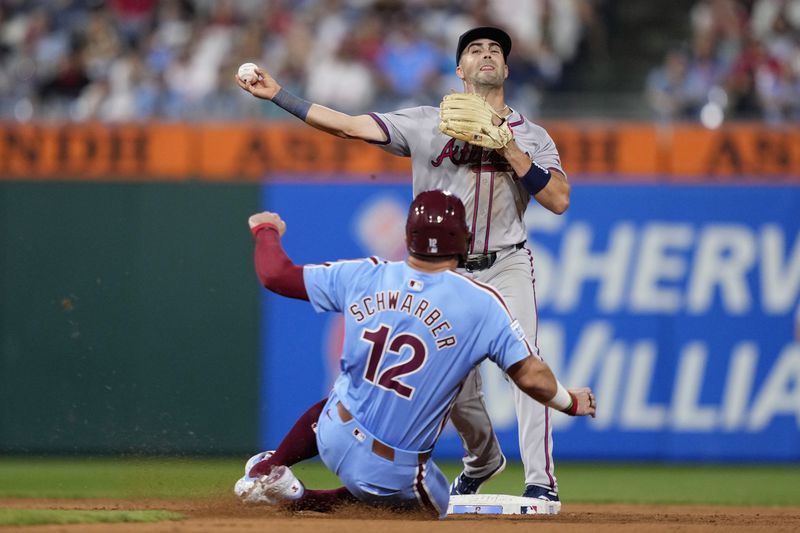 Atlanta Braves second baseman Whit Merrifield, top, throws to first after forcing out Philadelphia Phillies' Kyle Schwarber at second on a fielder's choice hit by Trea Turner during the fifth inning of a baseball game, Thursday, Aug. 29, 2024, in Philadelphia. (AP Photo/Matt Slocum)