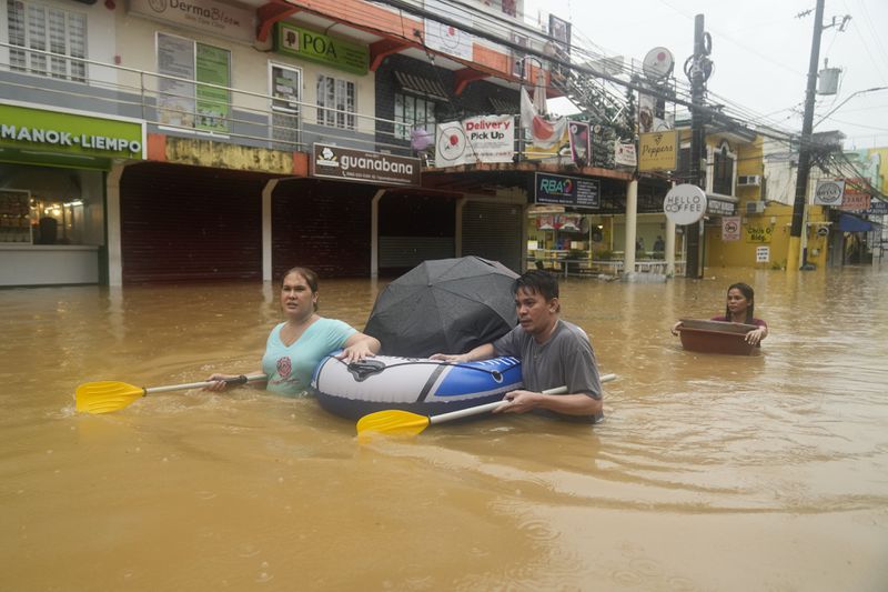 Residents use rubber paddles from a toy boat as they wade along a flooded street caused by heavy rains from Tropical Storm Yagi, on Monday, Sept. 2, 2024, in Cainta, Rizal province, Philippines. (AP Photo/Aaron Favila)