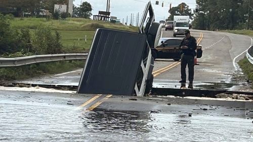 This photo provided by Brunswick County Sheriff's Office shows a police officer checking on a vehicle that fell into a sinkhole on a highway in Brunswick County, N.C., after a storm dropped historic amounts of rain, Monday, Sept. 16, 2024. (Brunswick County Sheriff's Office via AP)