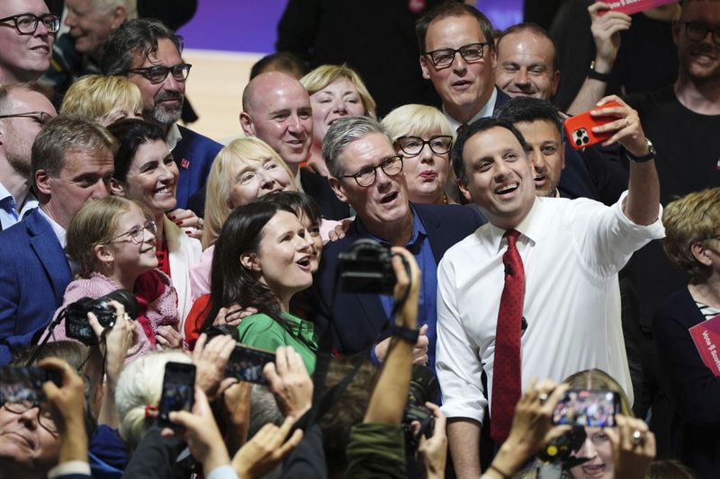 Britain's Labour Party leader Sir Keir Starmer and Scottish Labour leader Anas Sarwar, right, pose for a selfie during a visit to the Caledonian Gladiators Stadium in East Kilbride, Scotland, Wednesday July 3, 2024, while on the General Election campaign trail. (Andrew Milligan/PA via AP)