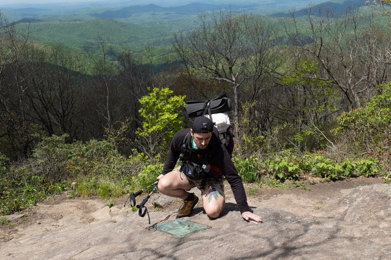 Zach Cross touches the first Appalachian Trail blaze at the Southern terminus on the top of Springer Mountain on Monday, May 1, 2023 just before he started his Appalachian Trail thru-hike.  (Ben Gray / Ben@BenGray.com)