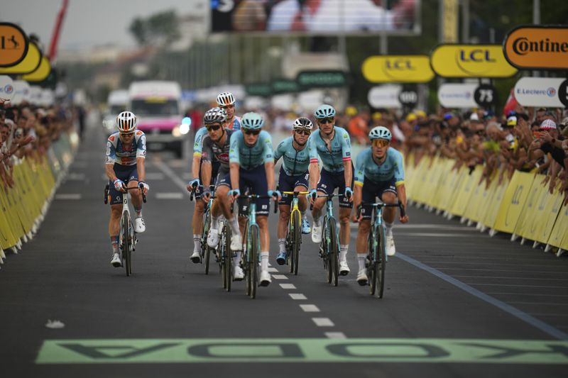 Britain's Mark Cavendish who was distanced by the pack, third right, is brought to the finish line by his Astana Qazaqstan Team in the first stage of the Tour de France cycling race over 206 kilometers (128 miles) with start in Florence and finish in Rimini, Italy, Saturday, June 29, 2024. (AP Photo/Daniel Cole)
