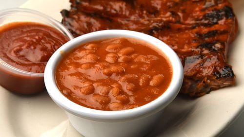 Fat Matt's Rib Shack's “Rum” Baked Beans, pictured with ribs, sauce and bread. 
(CHRIS HUNT FOR THE ATLANTA JOURNAL-CONSTITUTION)