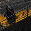 A spectator stands under driving range during a weather delay prior to an NFL football game between the Pittsburgh Steelers and the Dallas Cowboys, Sunday, Oct. 6, 2024, in Pittsburgh. (AP Photo/Matt Freed)