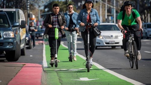 People ride LimeBike, left, and Bird electric scooters on the Embarcadero in San Francisco on April 13, 2018.