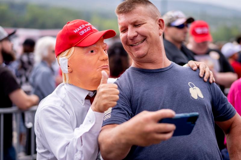 A supporter takes a selfie with a person wearing a Donald Trump mask before a campaign rally for Republican presidential nominee former President Trump at the Mohegan Sun Arena at Casey Plaza in Wilkes-Barre, Pa., Saturday, Aug. 17, 2024. (AP Photo/Laurence Kesterson)