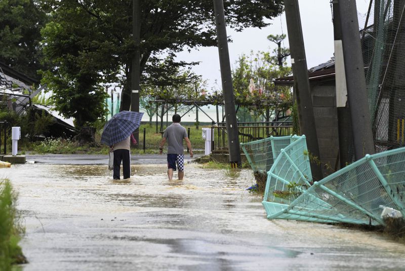 People wade through a partially flooded street in Suzu, Japan, Sunday, Sept. 22, 2024, following heavy rain in central Japan's Noto peninsula area, where a devastating earthquake took place on Jan. 1. (Kasumi Fukudome/Kyodo News via AP)