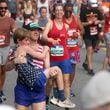 Young runner gets assist at the finish of the 55th running of the Atlanta Journal-Constitution Peachtree Road Race in Atlanta on Thursday, July 4, 2024.   (Jason Getz / AJC)