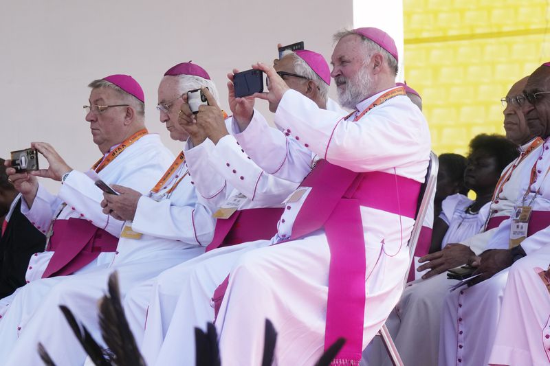 Clerics use their phones as Pope Francis gives an address during meeting with young people in the Sir John Guise Stadium in Port Moresby, Papua New Guinea, Monday, Sept. 9, 2024. (AP Photo/Mark Baker)