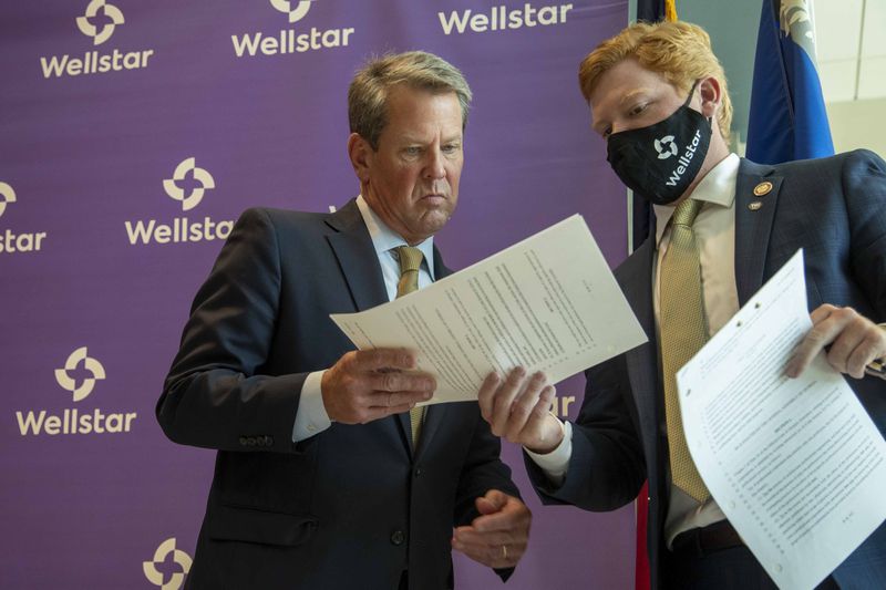 Gov. Brian Kemp’s intervention in the hospital fight is another sign of his behind-the-scenes strategy so far this legislative session.  In this 2020 photo, he is given a bill to sign following a ribbon cutting ceremony at the new Wellstar Kennestone Hospital Emergency Department building in Marietta. (Alyssa Pointer/The Atlanta Journal-Constitution)