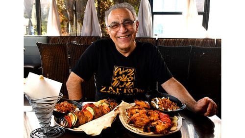 Peter Teimori, chef and owner of Zafron Restaurant in Sandy Springs, poses for a portrait with his (from left) bread, Kashk Bademjoon (eggplant spread with crispy mint and fried onions), Beef Shish Kebabs with grilled vegetables, Zafron Wings with grilled tomatoes, and a second serving of Kashk Bademjoon. (Styling by Peter Teimori / Chris Hunt for the AJC)