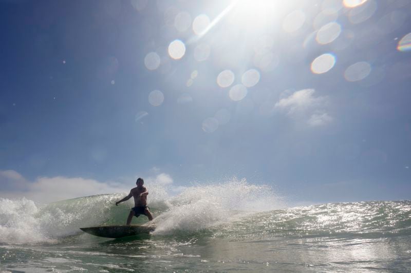 FILE - A surfer rides a wave at Windandsea Beach on May 30, 2024, in San Diego. Human-caused climate change intensified and made far more likely this month's killer heat with triple digit temperatures, a new flash study found Thursday, June 20. (AP Photo/Gregory Bull, File)