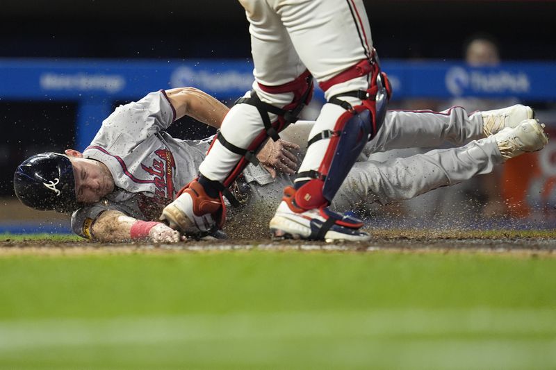 Atlanta Braves' Jarred Kelenic, left, touches home plate to score off a fielder's choice hit by teammate Matt Olson during the 10th inning of a baseball game against the Minnesota Twins, Tuesday, Aug. 27, 2024, in Minneapolis. (AP Photo/Abbie Parr)