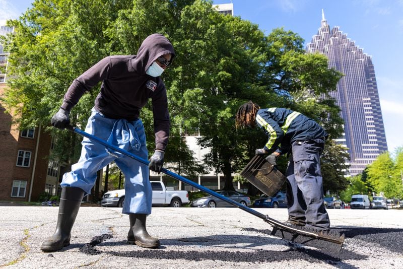 Atlanta Department of Transportation construction maintenance worker Rico Gooden and equipment operator Quincy Roberts fix a pothole in Atlanta on Tuesday, April 25, 2023. (Arvin Temkar / arvin.temkar@ajc.com)