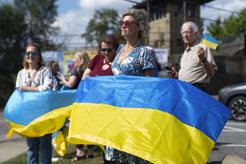 Kristina Ramanauskas, a first generation Lithuanian, waves a Ukrainian flag before President of Ukraine Volodymyr Zelenskyy's motorcade arrives at the Scranton Army Ammunition Plant in Scranton on Sunday, Sept. 22, 2024. (AP Photo/Laurence Kesterson)