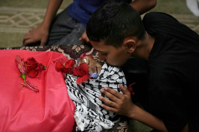 A Palestinian mourner takes the last look at the body of Mohammad Hoshiya, 12, during his funeral in the West Bank village of Qatana, southwest of Ramallah Saturday, June 22, 2024. Hoshiya succumbed to his wounds sustained during an Israeli army raid in the refugee camp of Amari last week, Palestinian ministry of health said. (AP Photo/Nasser Nasser)