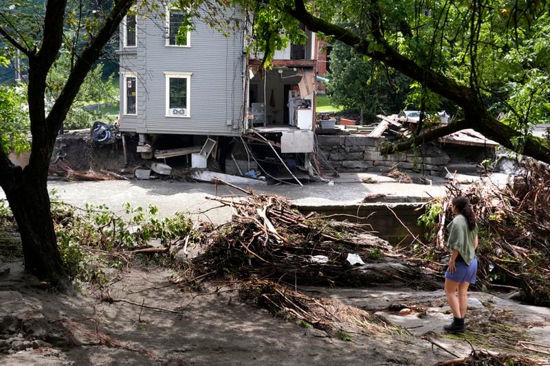 A woman looks at what remains of an apartment building, of which about one third of the building broke away and was carried downstream, after remnants of Hurricane Beryl caused flooding and destruction, Friday, July 12, 2024, in Plainfield. (AP Photo/Charles Krupa)