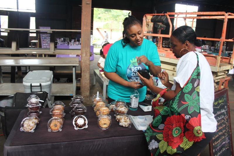 A vendor sells baked goods to a customer at the Vegan Social event in East Point, Ga.
