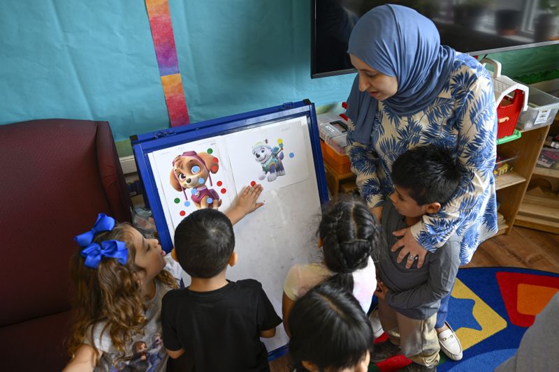 Preschool teacher Tinhinane Meziane, right, watches her students discuss the results on voting the most popular character of the TV show PAW Patrol at the ACCA Child Development Center, Thursday, Sept. 19, 2024, in Annandale, Va. The students are getting foundational lessons on how to live in a democracy by allowing them to regularly vote on different things through out the day. (AP Photo/John McDonnell)