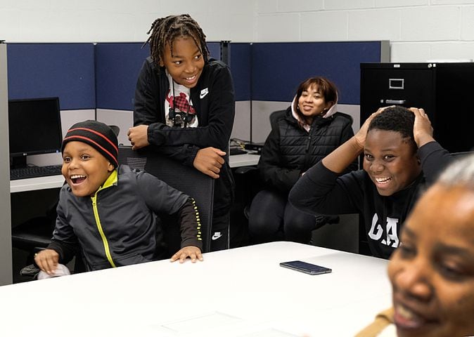 Brendan Dozier, 10 on the left  and Zalen Clay, 13, far right, right, react when they hear they have gotten gift cards to Academy. Carson Beck was on site at an Athens Academy store Sunday December 17, 2023, to give out gift cards to lucky members of area Boys and Girls Clubs. Academy contributed $200 for each child and he kicked in $135 more of his own money to help families out. 

credit: Nell Carroll for the AJC