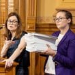 Kristin Nabers (left), state director for All Voting is Local, opposed a new rule seeking a hand count of ballots during a September meeting of the State Election Board at the Georgia Capitol as colleague Marissa Pyle holds 1,872 pieces of paper to demonstrate what a stack of ballots might look like. “Counting thousands of ballots by hand will be an incredibly tedious, expensive and possibly error-prone process,” Nabers said. “Any human errors can be exploited by election deniers to sow distrust and decrease confidence in our elections and in the hardworking election officials that run them.” (Arvin Temkar/AJC)