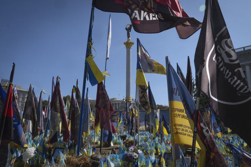 Flags with the names of killed soldiers are carried at a makeshift memorial for fallen Ukrainian soldiers in the Russian-Ukrainian war during Ukrainian Independence Day on Independence Square in Kyiv, Ukraine, Saturday, Aug. 24, 2024. (AP Photo/Efrem Lukatsky)