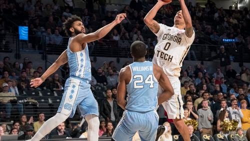 Georgia Tech guard Justin Moore (0) shoots against the defense of North Carolina guard Kenny Williams (24) and guard Joel Berry, during the second half of an NCAA college basketball game, Saturday, Dec 31, 2016, in Atlanta. Georgia Tech won 75-63. (AP Photo/John Amis)