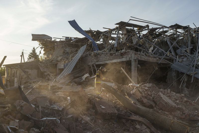 A firefighter collects fragments of a rocket after a Russian strike on the Sapphire hotel in Kramatorsk, Donetsk region, Ukraine, Sunday, Aug. 25, 2024. (AP Photo/Evgeniy Maloletka)