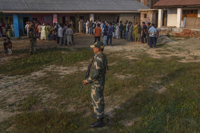 An Indian paramilitary soldier stands guard as Kashmiri's queue up at a polling booth to cast their vote during the second phase of the assembly election in the outskirts of Srinagar, Indian controlled Kashmir, Wednesday, Sept. 25, 2024. (AP Photo/Dar Yasin)