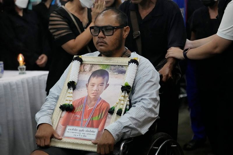 Victims' relatives carry portraits of the victims of a bus fire in a procession at Wat Khao Phraya Sangkharam School Lan Sak, Uthai Thani province, Thailand, Thursday, Oct. 3, 2024. (AP Photo/Sakchai Lalit)