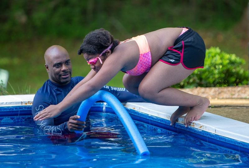 SwemKids instructor Ezra Jones watches Honesty Mincey (age 11) dive (CQ according to organizer). After COVID shuttered pools, a Fayetteville man offered his backyard pool for swimming instruction & water safety lessons to Atlanta city kids. SwemKids is a nonprofit that offers free swimming gear & lessons as an in-school program for kids in low income neighborhoods.  PHIL SKINNER FOR THE ATLANTA JOURNAL-CONSTITUTION.