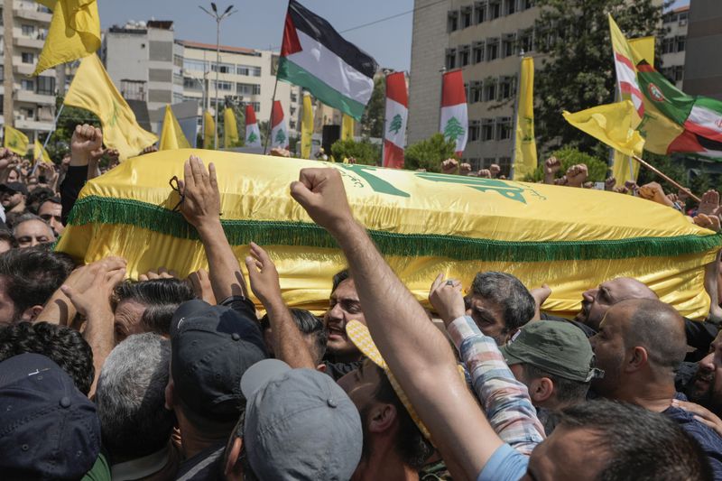 People carry the coffin of Hezbollah senior commander Taleb Sami Abdullah, 55, known within Hezbollah as Hajj Abu Taleb, who was killed late Tusday by an Israeli strike in south Lebanon, during his funeral procession in the southern suburbs of Beirut, Lebanon, Wednesday, June 12, 2024. Hezbollah fired a massive barrage of rockets into northern Israel on Wednesday to avenge the killing of the top commander in the Lebanese militant group as the fate of an internationally-backed plan for a cease-fire in Gaza hung in the balance. (AP Photo/Bilal Hussein)