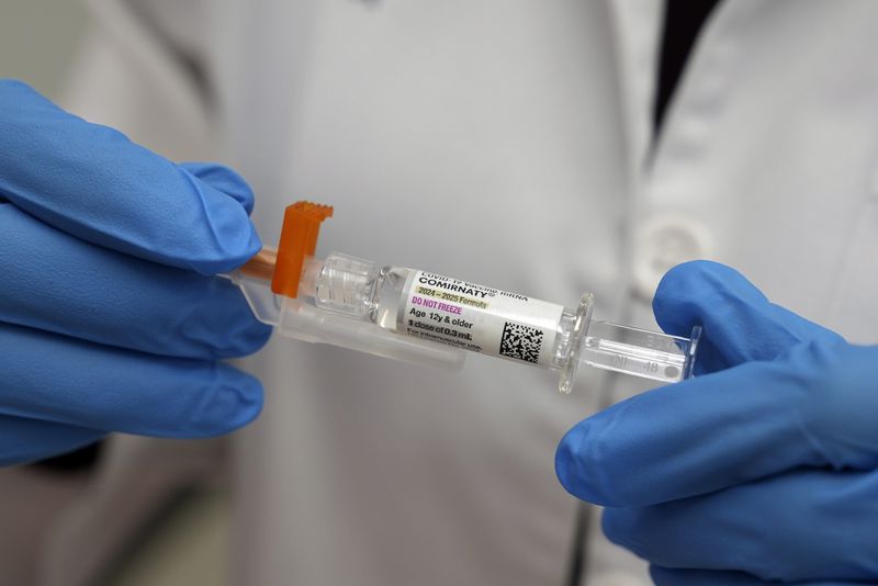 A pharmacist holds a COVID-19 vaccine at a pharmacy in New York, Tuesday, Sept. 24, 2024. (AP Photo/Mary Conlon)